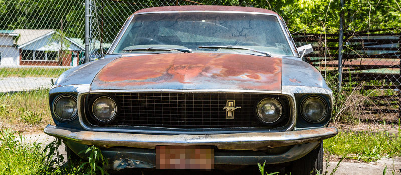Rusted Ford Mustang and other salvaged cars for sale in a lot