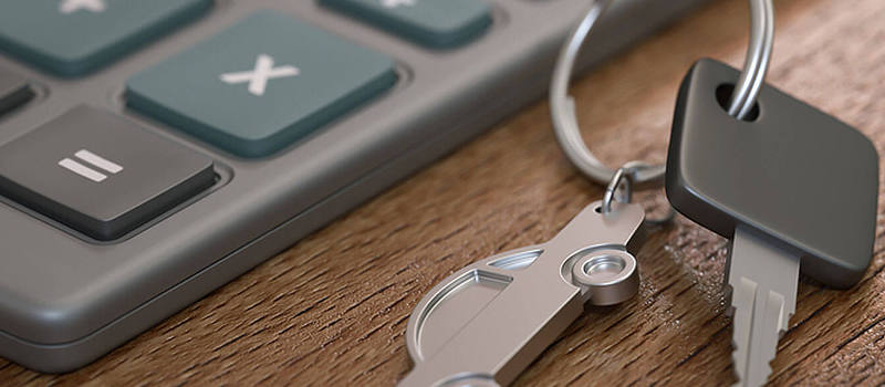 Close up photograph of a set of car keys next to a calculator as both buyer and seller uses Kelly Blue Book to find the right price.