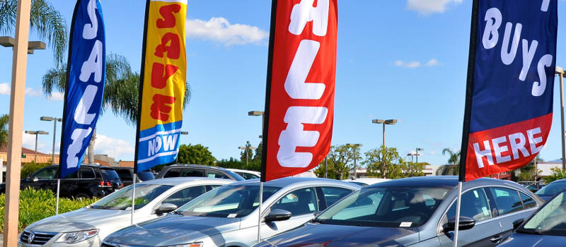 car dealership with sales signs up on a sunny day.